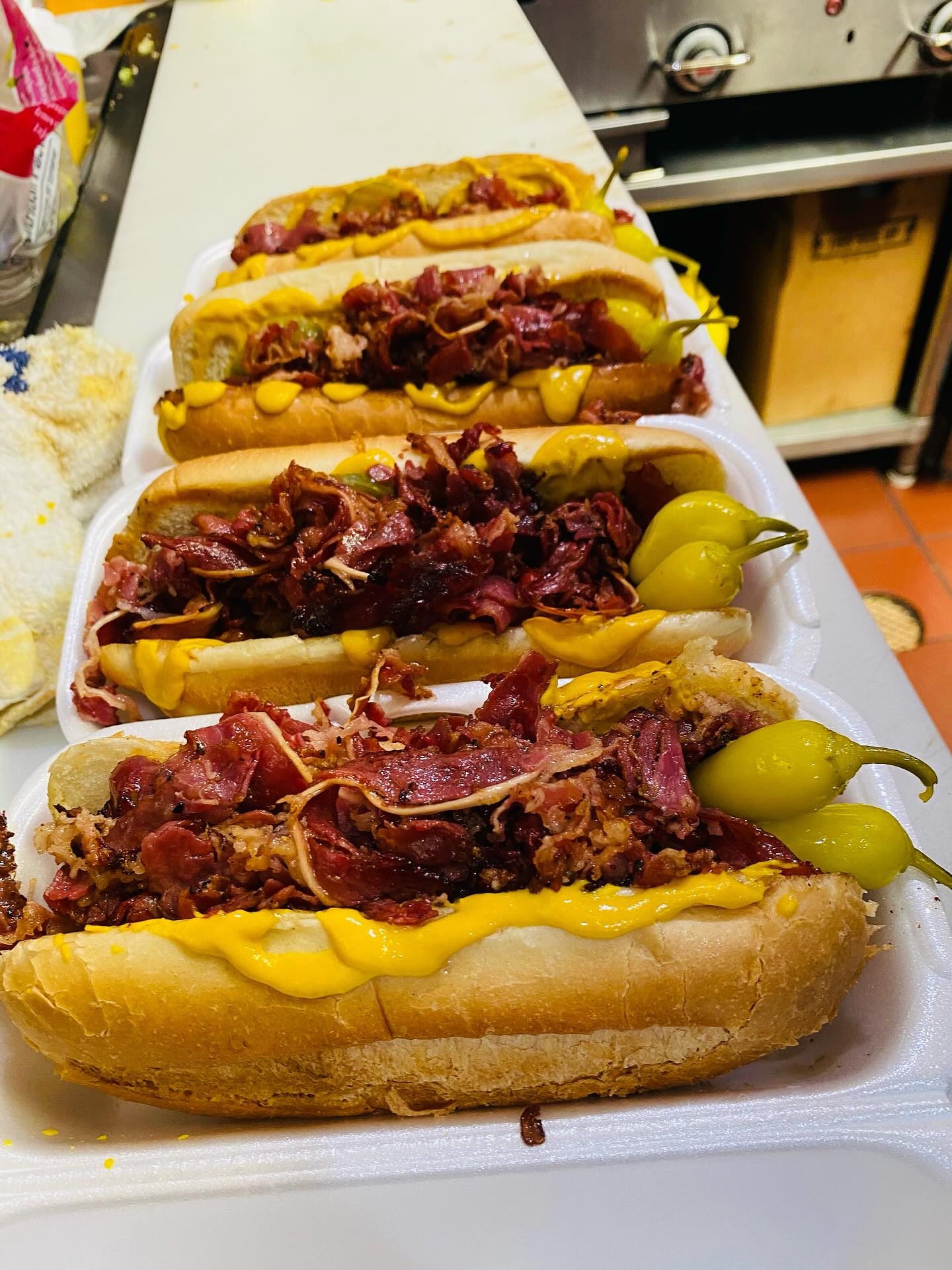 Row of pastrami beef hot dogs with mustard and sport peppers