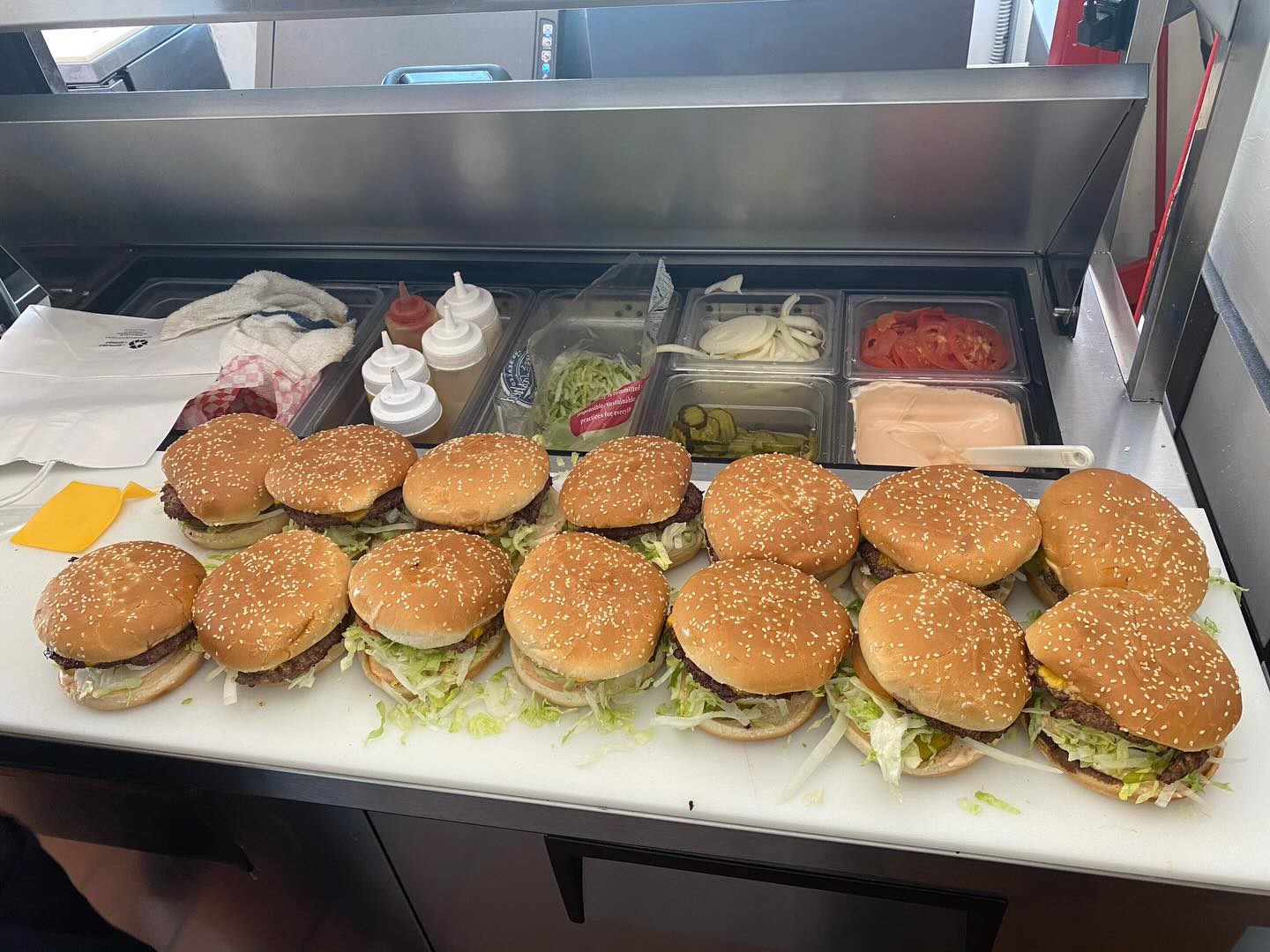 Catering prep line with burgers lined up for a large order