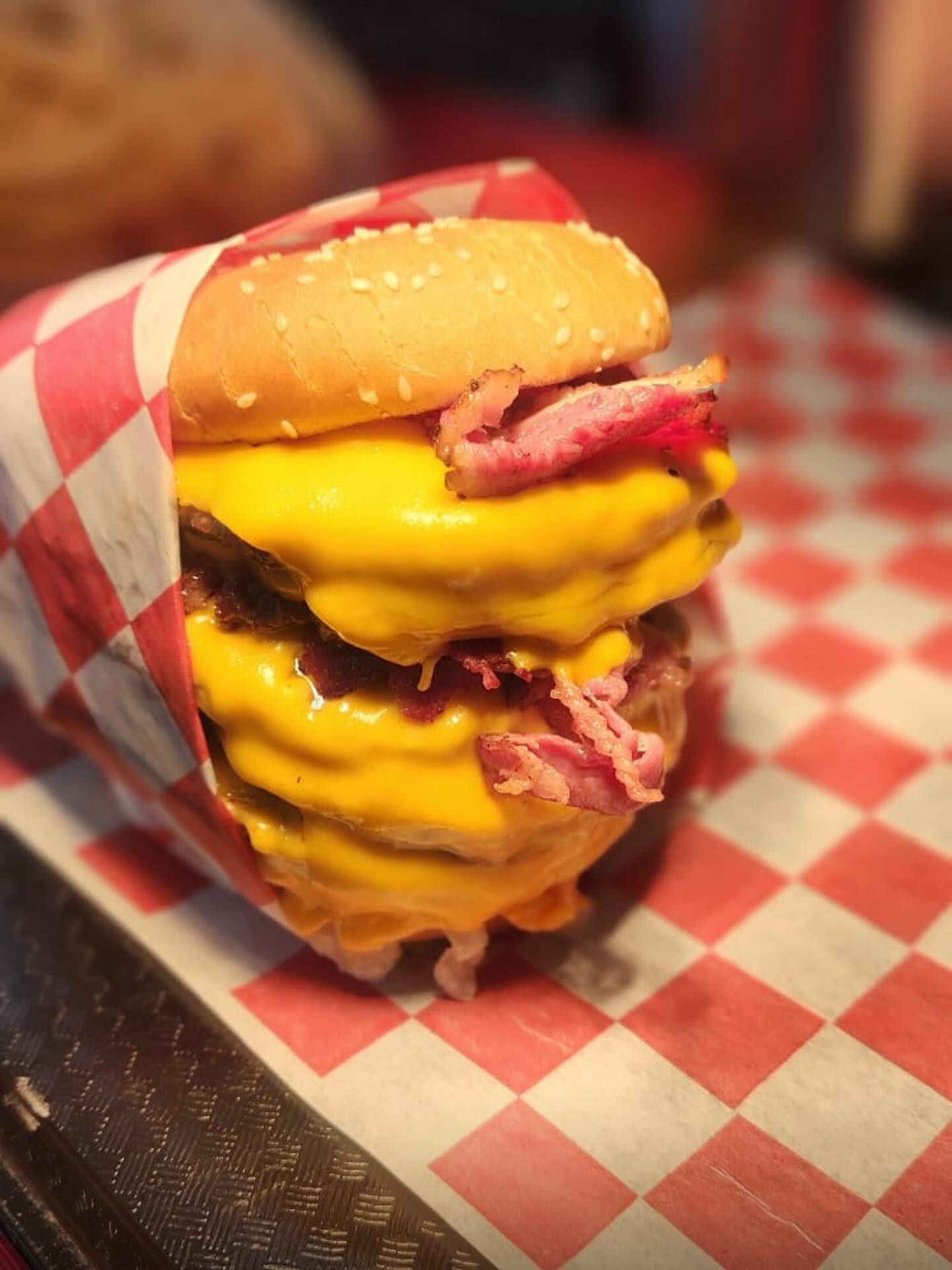 Stacked beef bacon burger wrapped in red checkered paper